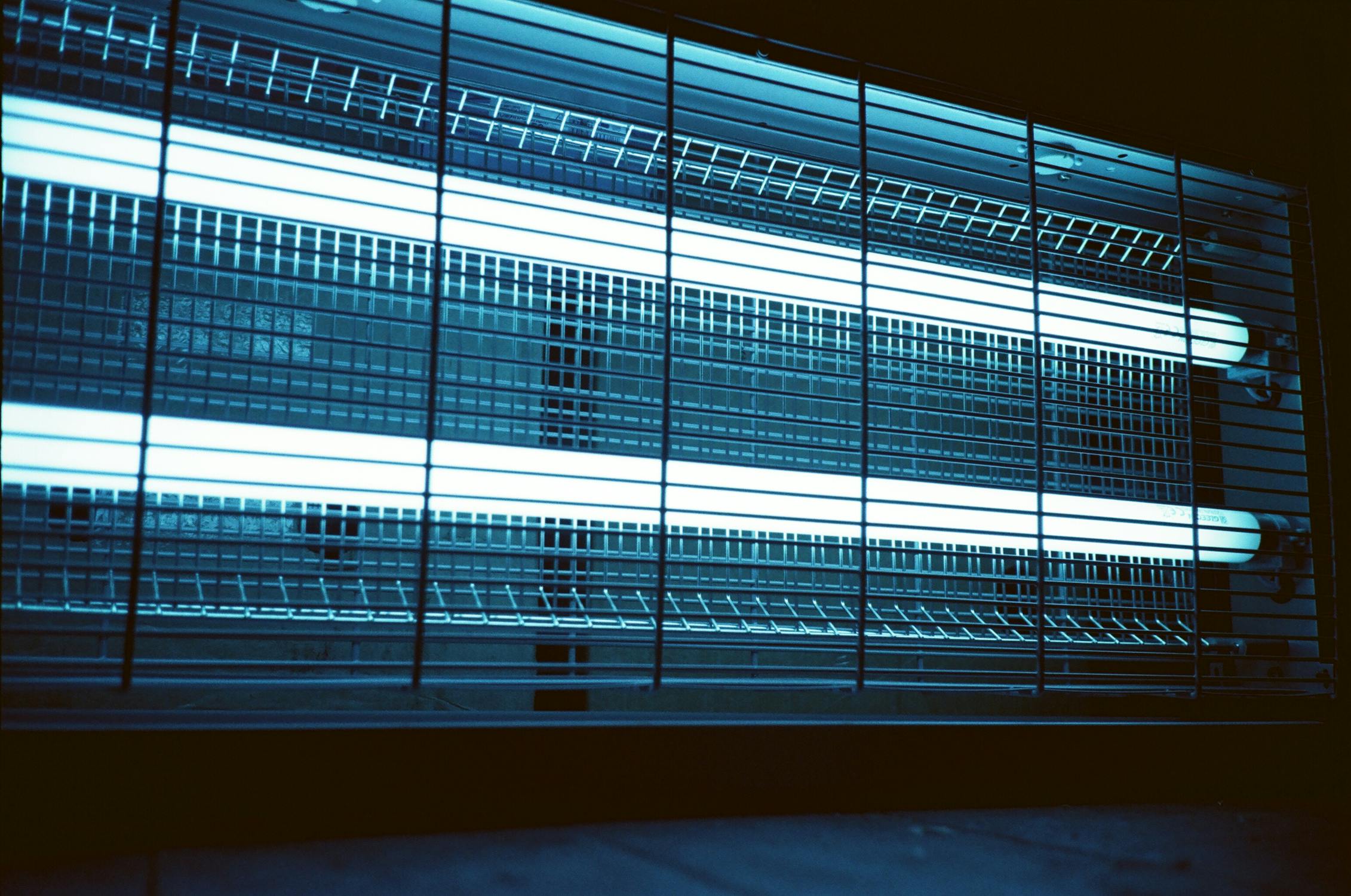 Industrial fluorescent tube lights behind a wire mesh cage guard