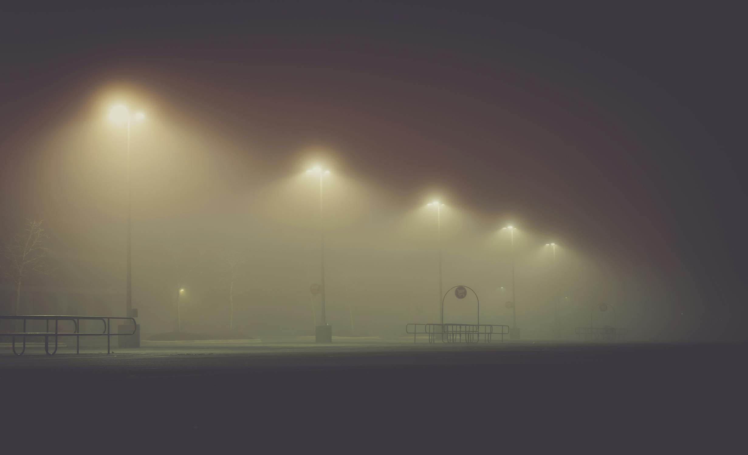 Row of warm amber HPS street lamps glowing through fog at night